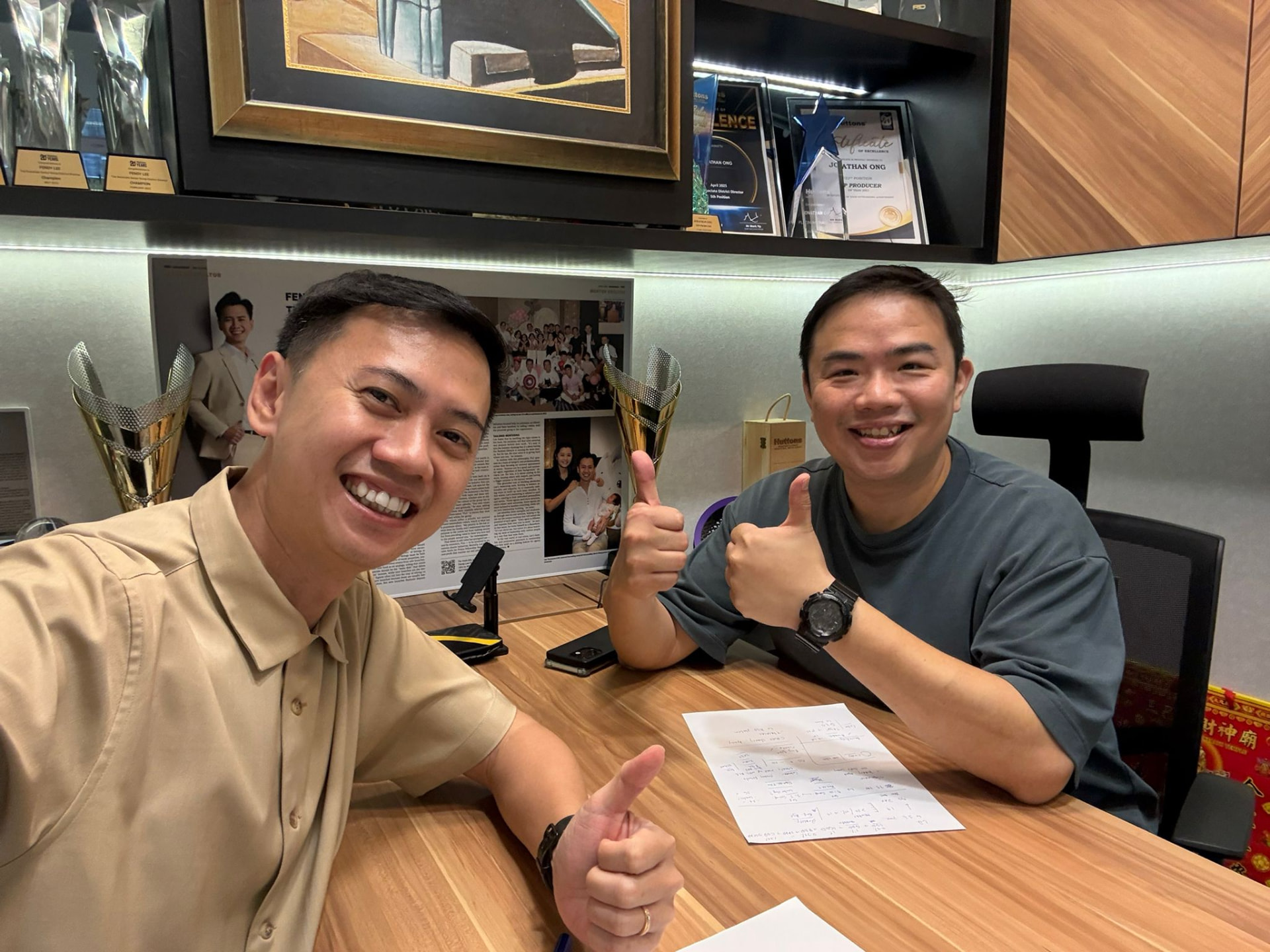 Fendy and a colleague reviewing plans at a desk with awards behind them