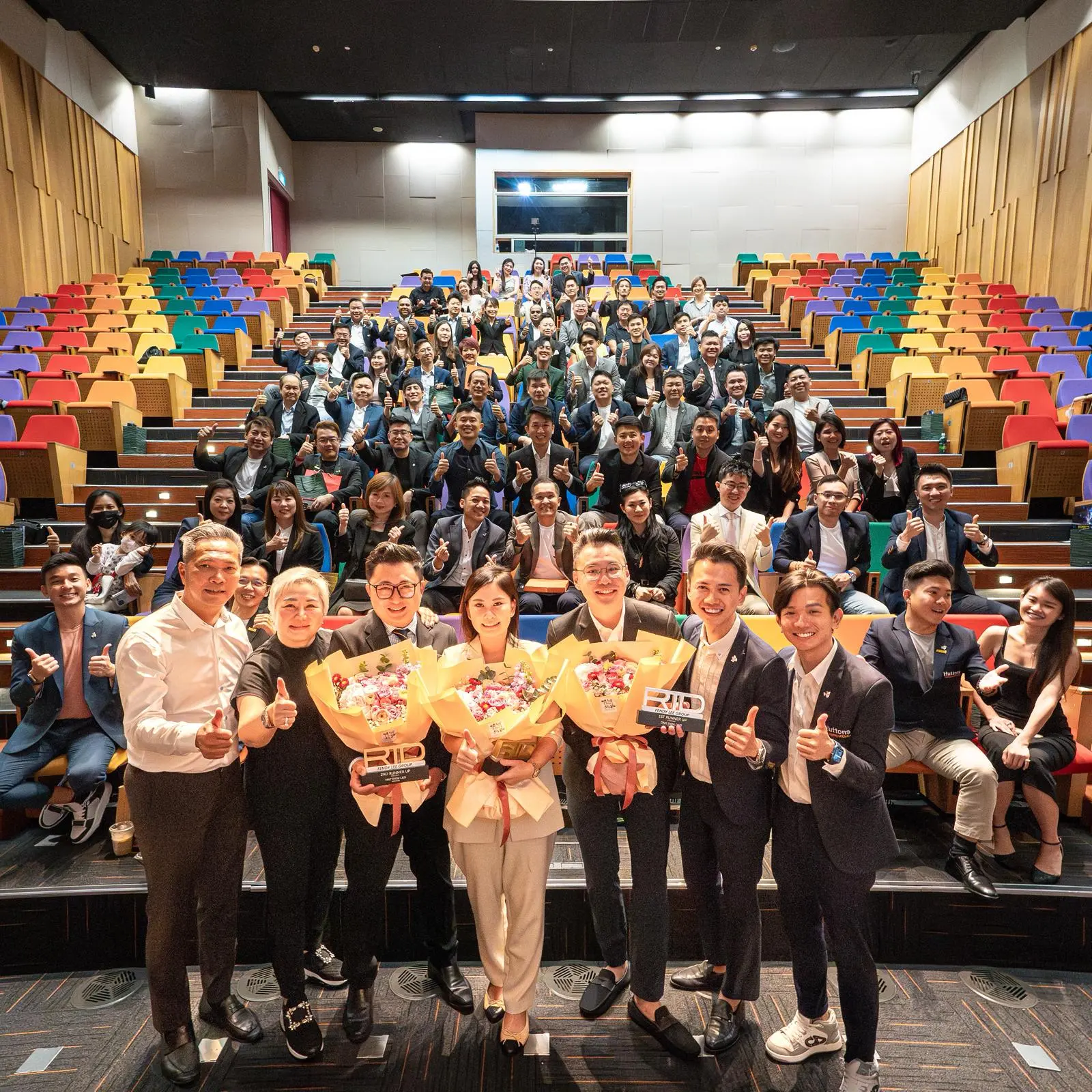 Fendy Lee Group on stage at an awards ceremony with colourful auditorium seating
