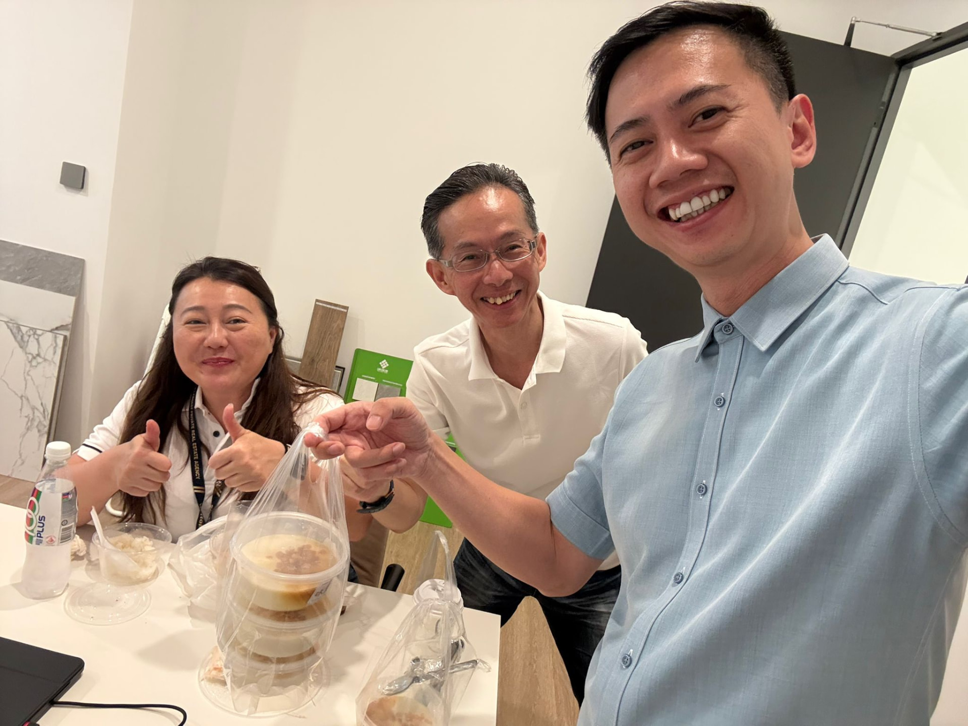 Fendy Lee taking a casual selfie with two colleagues over food and drinks in a bright office setting