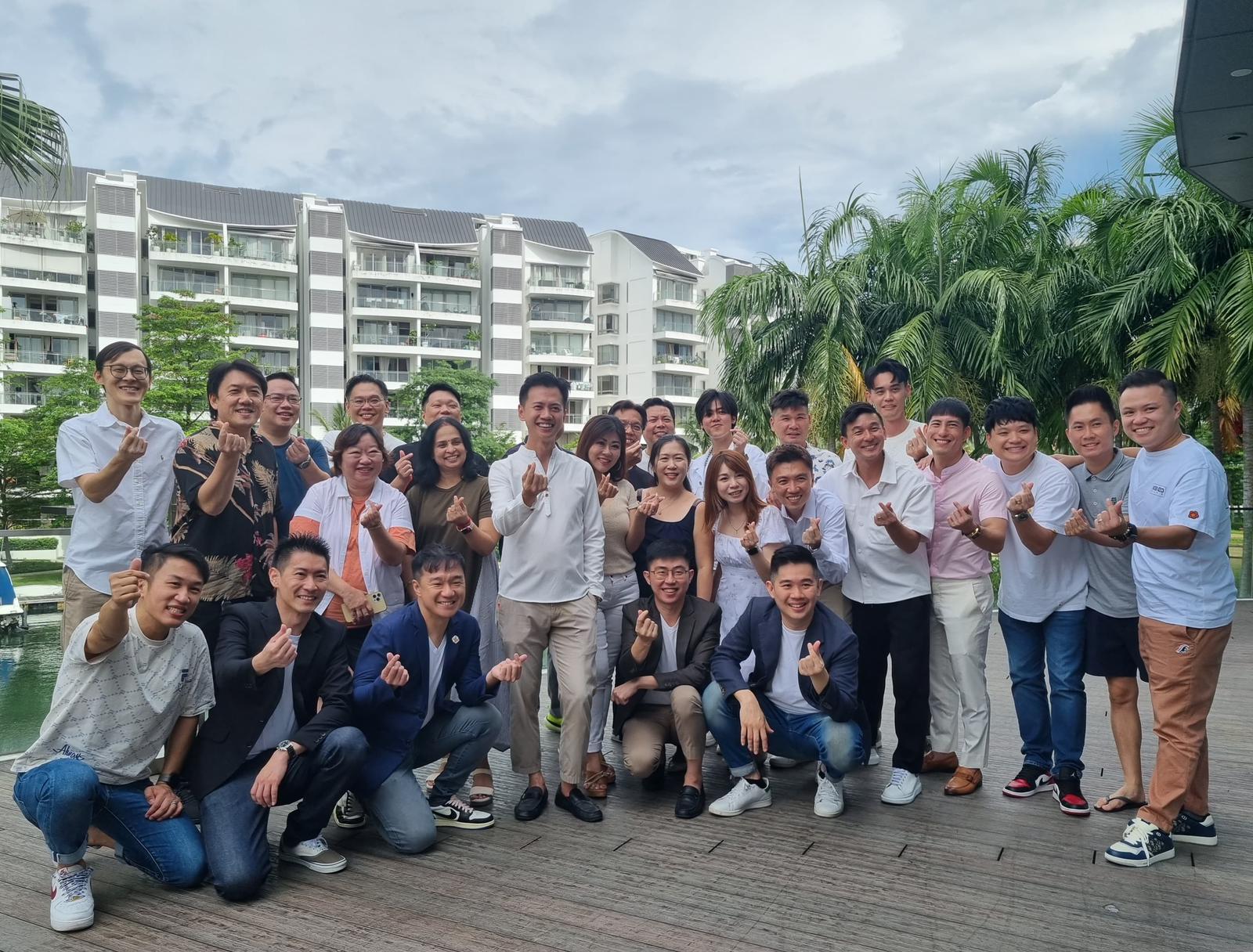 The Fendy Lee Group team gathered outdoors in front of a condominium, smiling and giving thumbs up